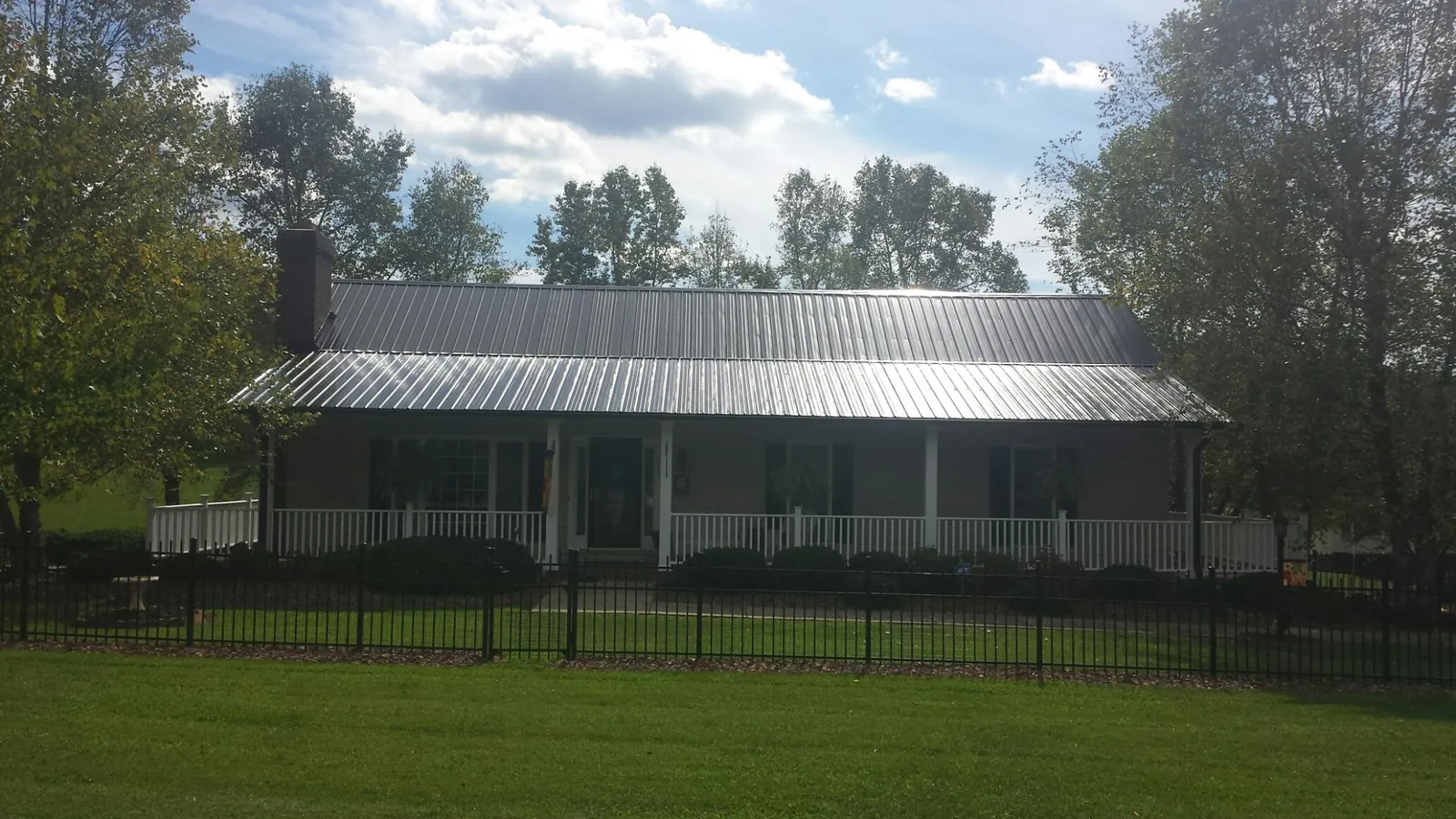Gray metal roof on a brick ranch with a full width front porch — Gutter Guard Installation work by our crew in Sharpsburg